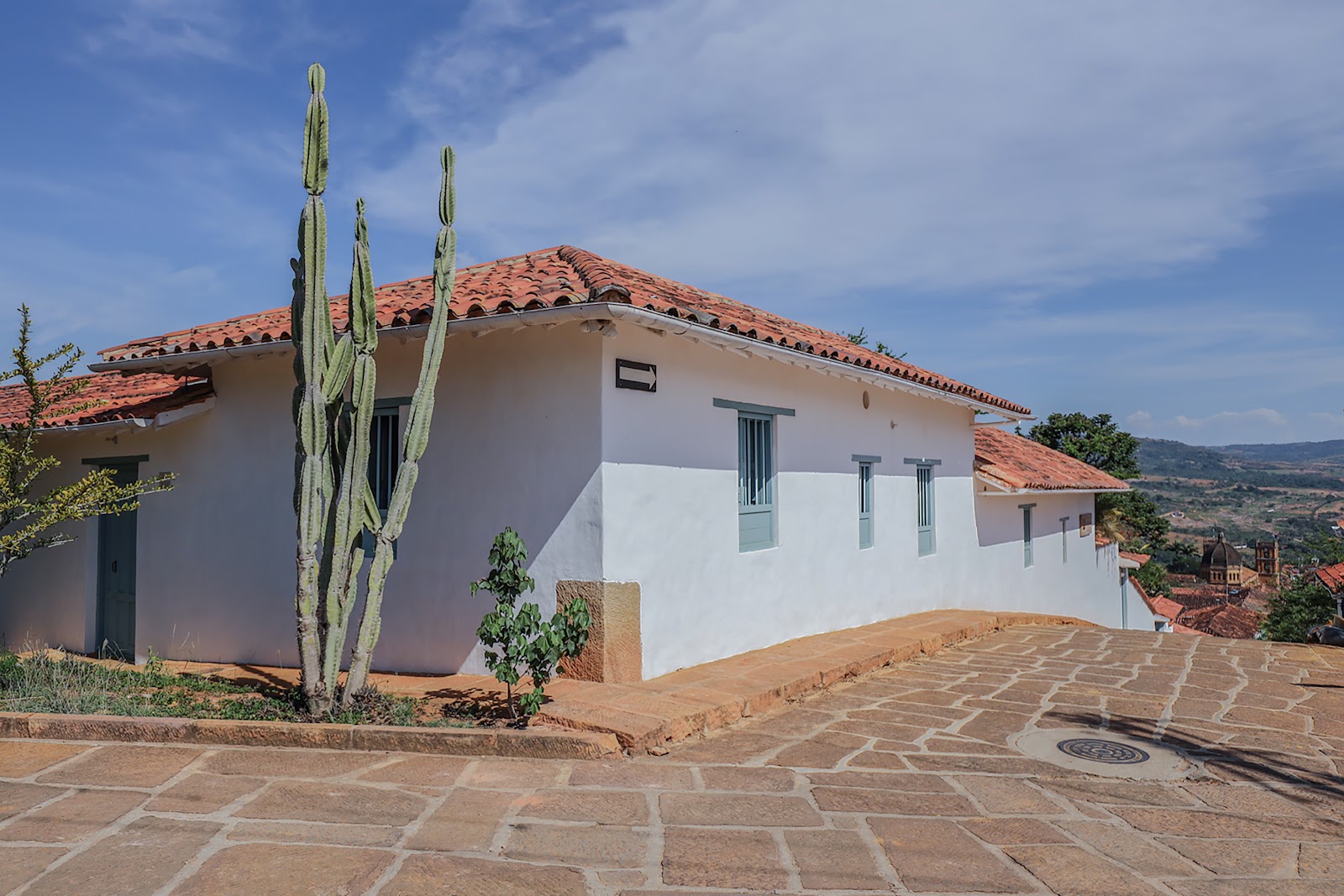 Fachada blanca de Casa Barichara con ventanas azules y cactus