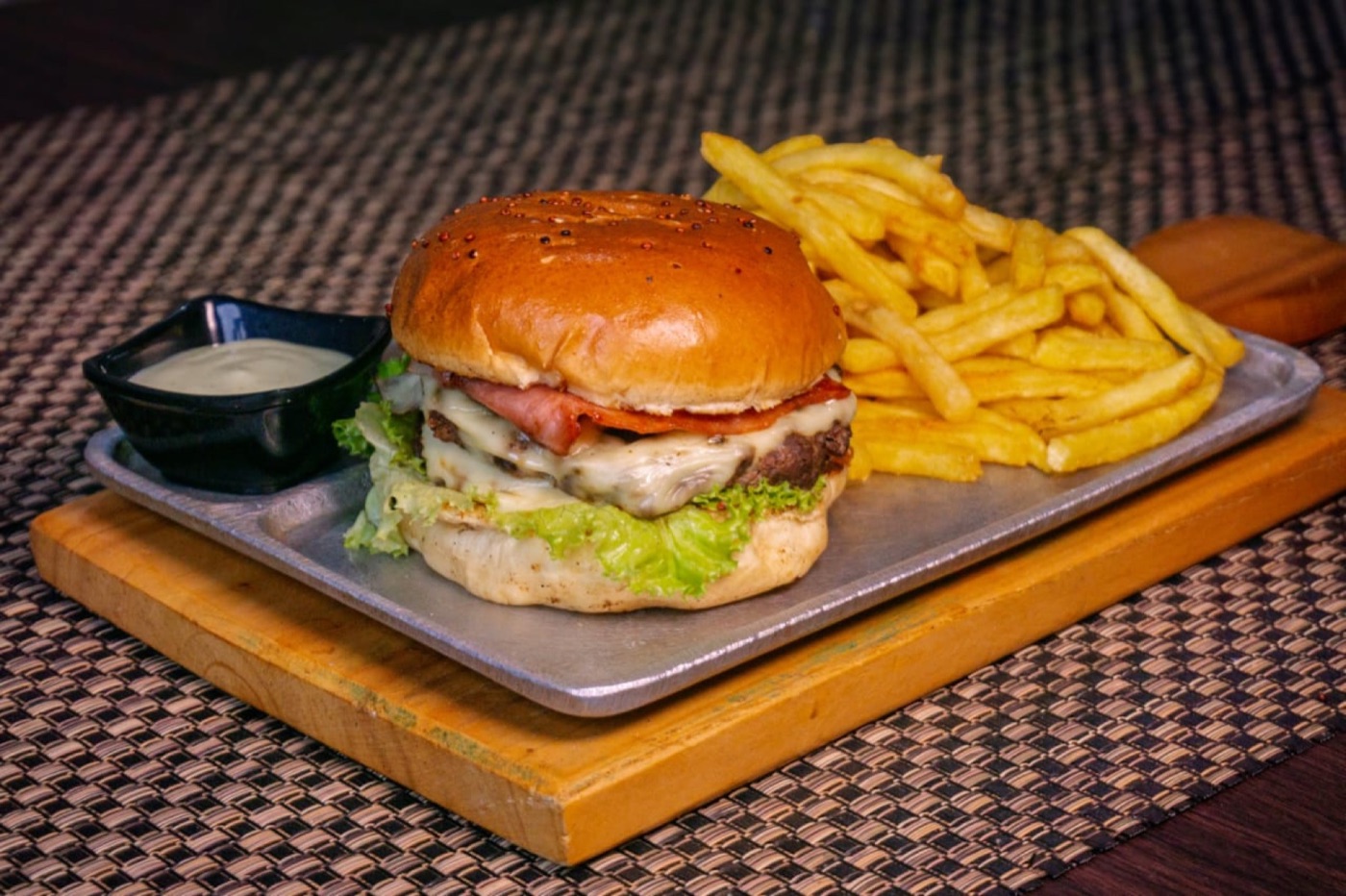 Hamburguesa con tocineta y papas a la francesa sobre tabla de madera