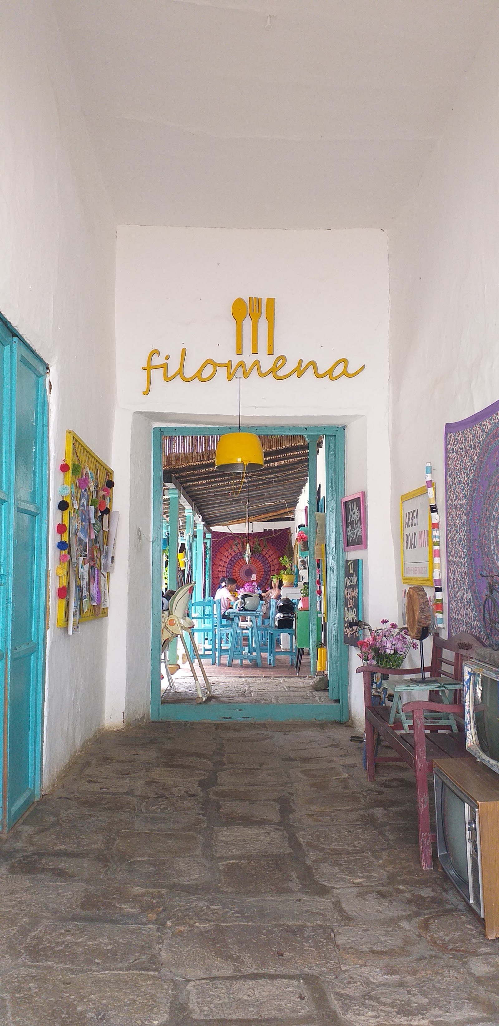 Entrada de Filomena: pasillo blanco con marcos turquesa y letrero dorado