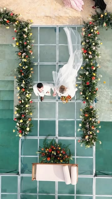 Novios vistos desde arriba sobre una pasarela entre flores