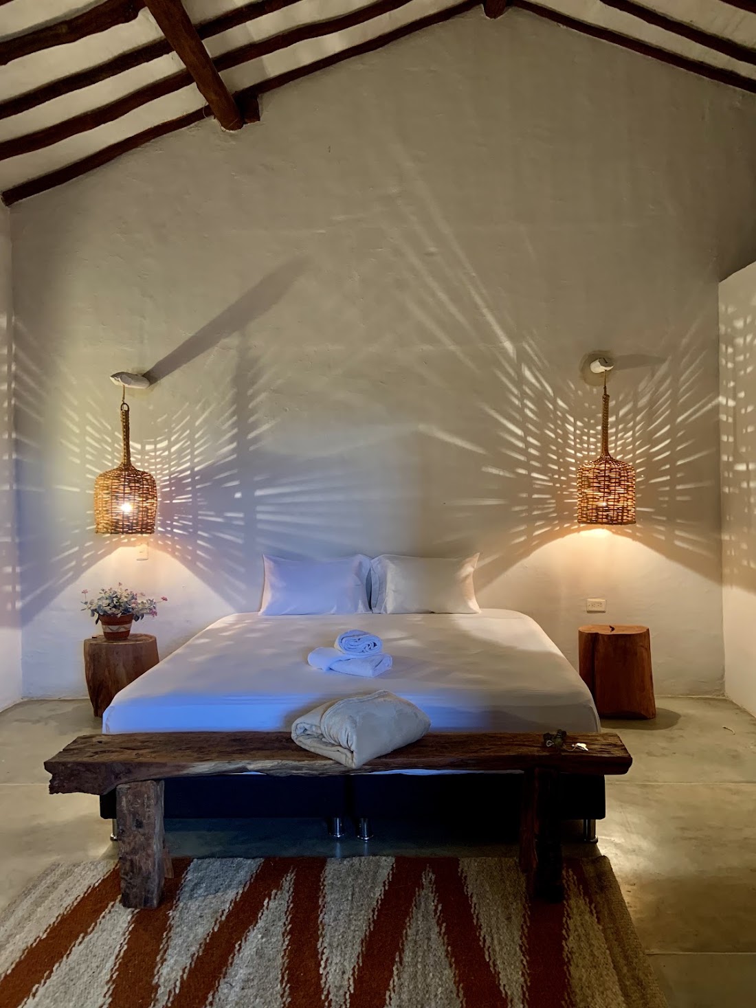 Habitación con lámparas que dibujan sombras en la pared y cama amplia