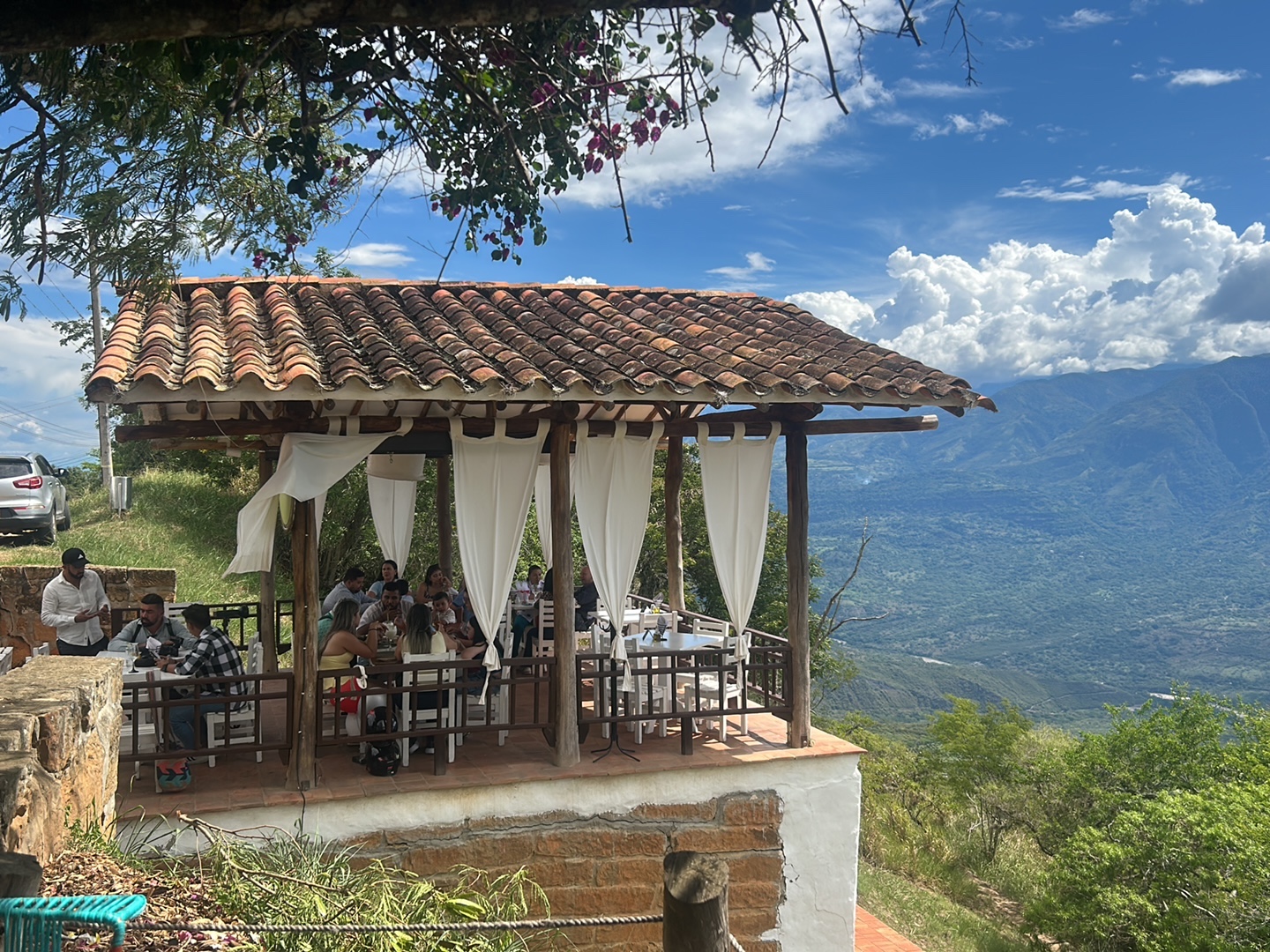 Kiosco con techo de teja y cortinas blancas al borde del mirador