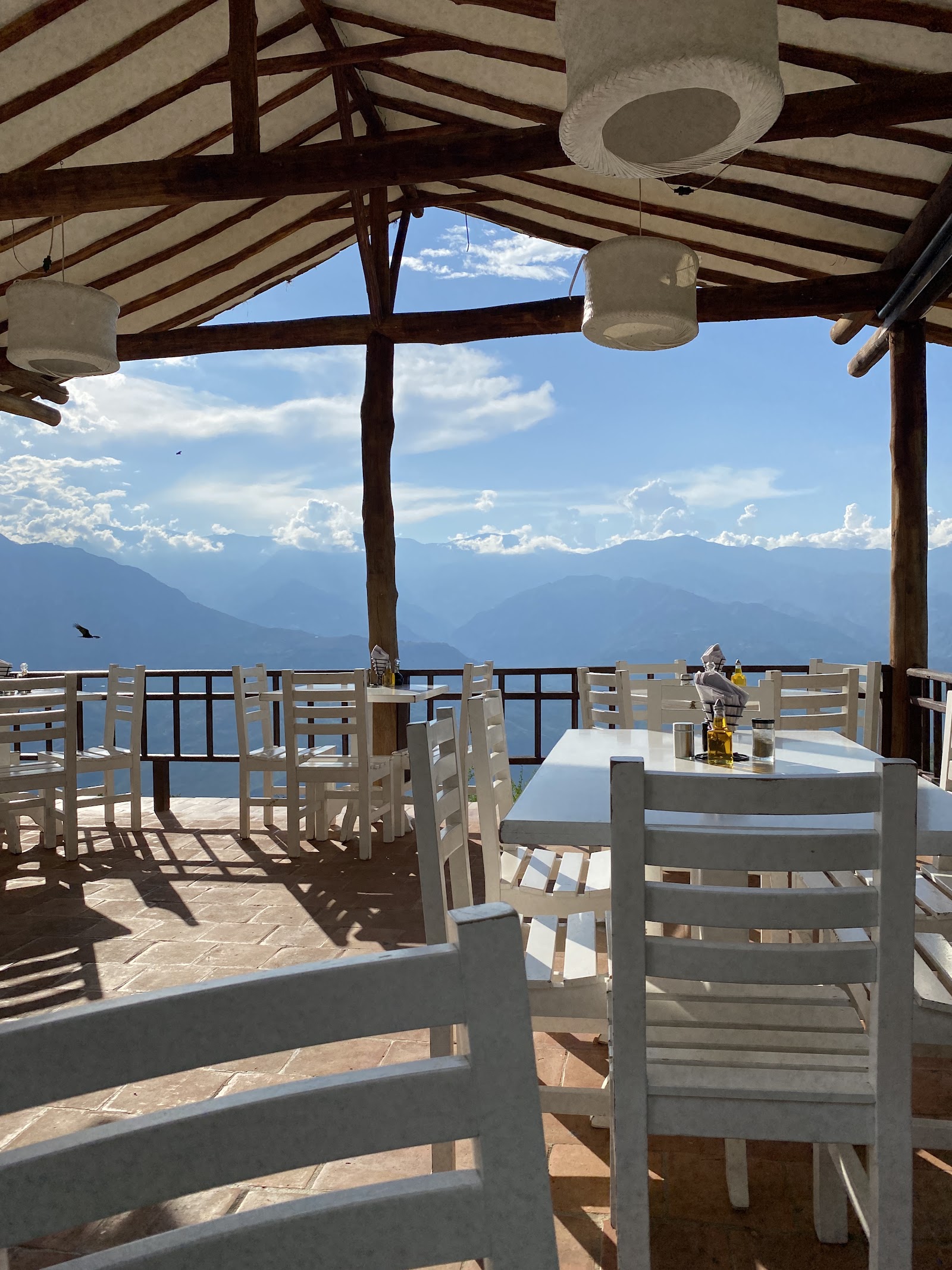 Mesas blancas bajo el kiosco con las montañas al fondo