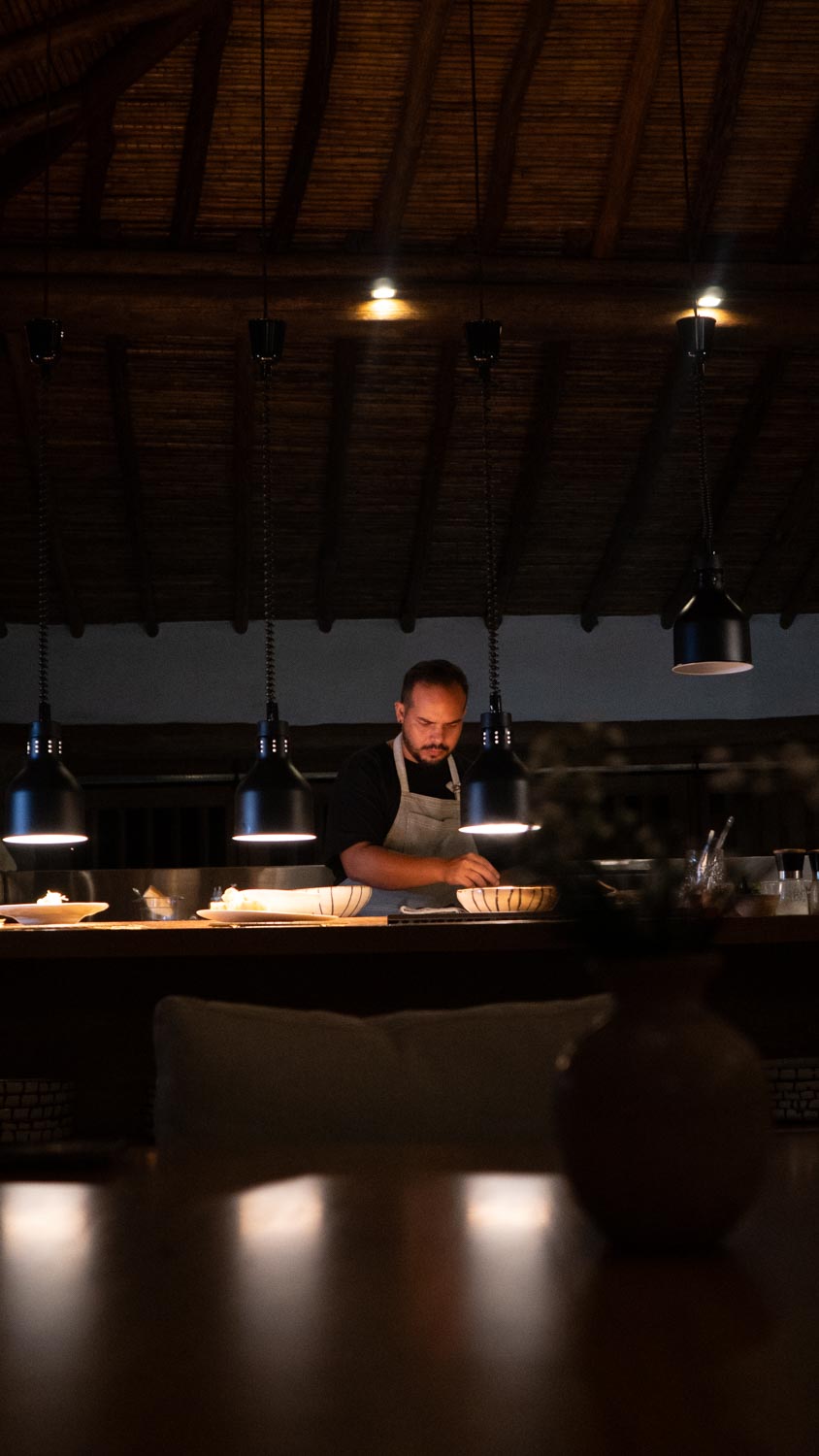 El chef trabajando en la cocina abierta de Lucia, bajo lámparas colgantes