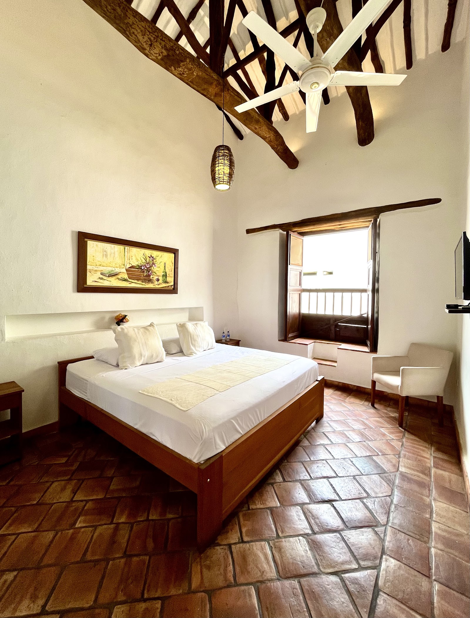 Habitación con cama doble, techo de madera y ventana colonial