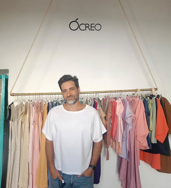 Cliente con camiseta blanca de lino y algodón frente al perchero de Ócreo