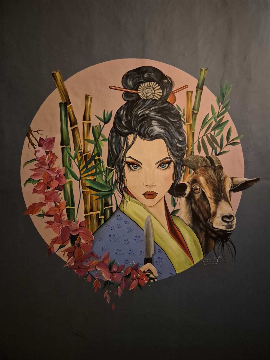 Mural de Sierra: una mujer de estilo asiático junto a una cabra santandereana, entre bambúes y flores