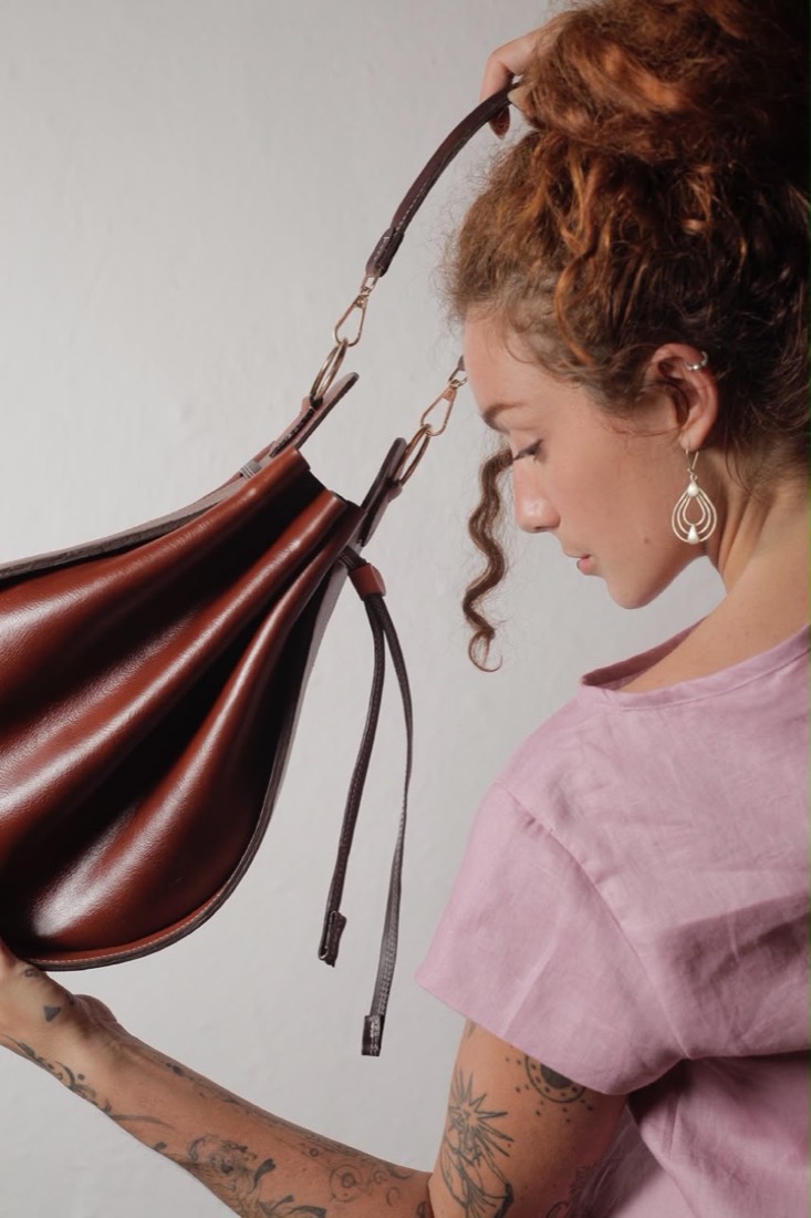 Bolso Barachalá en cuero marrón frente a una puerta turquesa