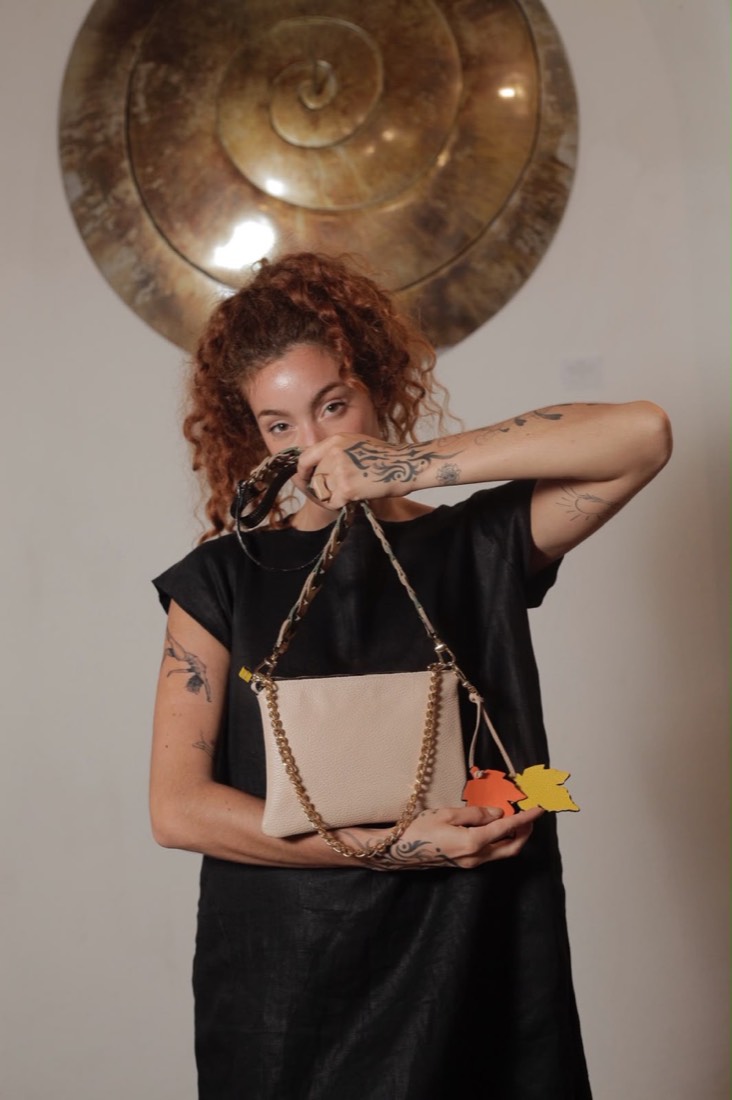 Modelo con el bolso Guane en cuero beige frente a un disco de bronce